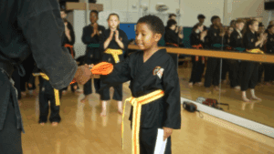 Image of a boy receiving his orange belt